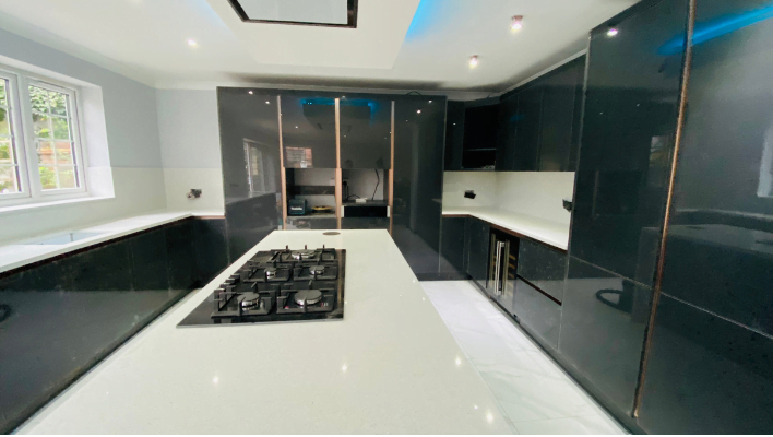 High-gloss anthracite kitchen in Wembley with bronze-effect trim and white quartz island