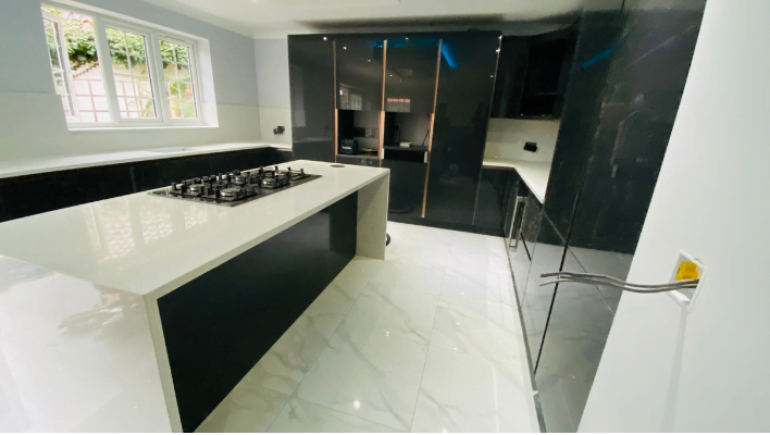 Second view of high-gloss anthracite kitchen in Wembley with bronze trim and blue LED lighting