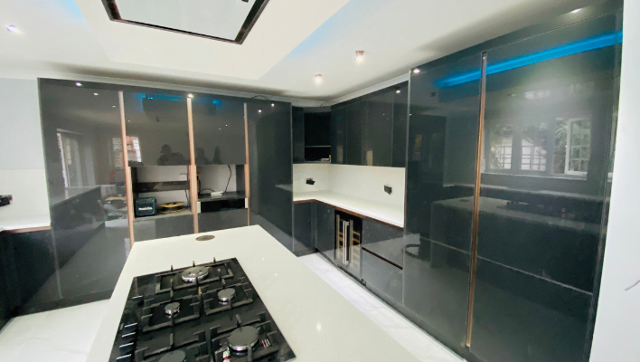 Third view of high-gloss anthracite kitchen in Wembley with bronze trim and blue LED lighting