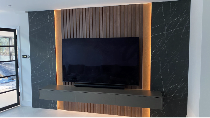 Detail view of backlit walnut panel and black marble-effect wall either side, Chesham