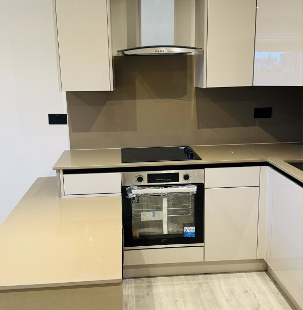 Second view of cream gloss handleless kitchen in Ilford with stacked fridge, oven and microwave tower