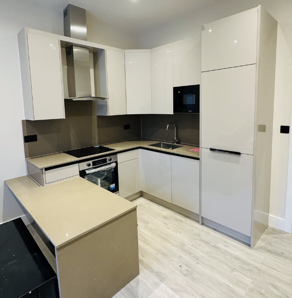 Third view of cream gloss handleless kitchen in Ilford showing ceramic hob and extractor