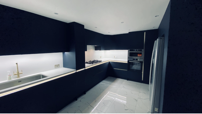 Full layout view of handleless navy kitchen in Edgware showing L-shape, appliance tower, American fridge freezer and LED under-cabinet lighting
