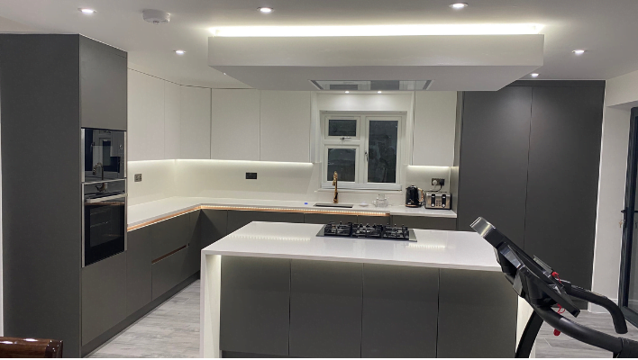 Matt khaki-green handleless kitchen in Isleworth with waterfall-edge quartz island and bifold doors to garden