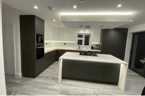 Second view of matt khaki-green handleless kitchen in Isleworth with waterfall quartz island