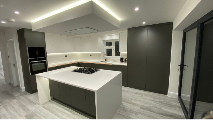 Third view of matt khaki-green handleless kitchen in Isleworth with waterfall quartz island