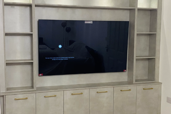 Grey concrete-effect media wall in Harrow with recessed TV niche, open shelving and brass-handle cabinets