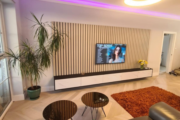 Close view of oak slatted media wall in London with LED strip lighting and floating TV unit