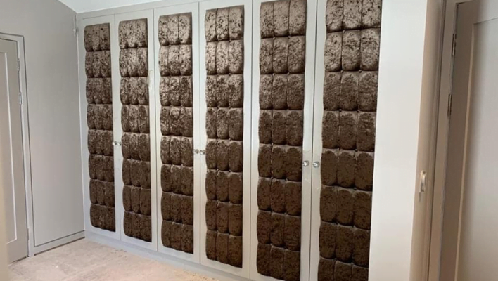 Floor-to-ceiling four-door matt stone and cream wardrobe with black-framed edging and vertical pull handles