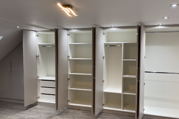 White matt wardrobe carcassed to a sloped loft ceiling with hinged doors following the roofline