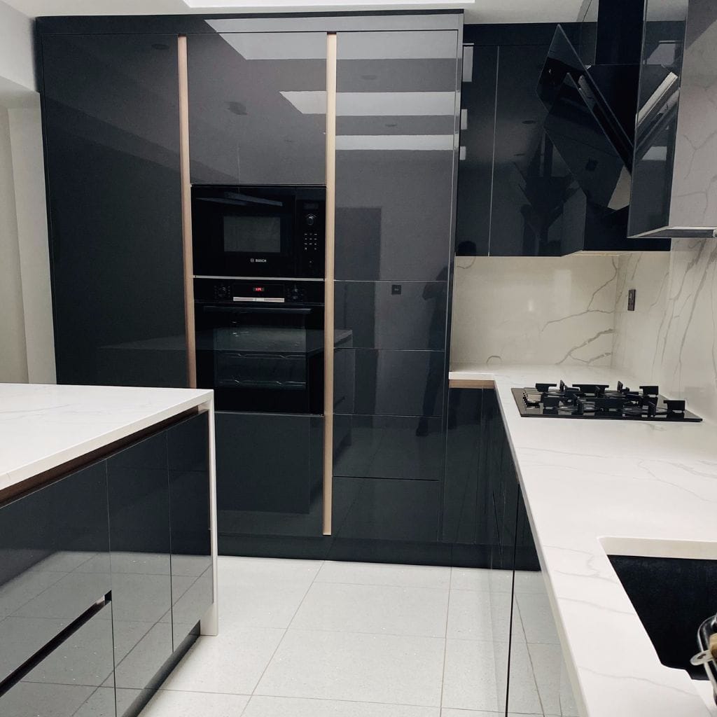 Handleless black gloss kitchen with full-height integrated appliance tower, Bosch oven and microwave, and white quartz worktops