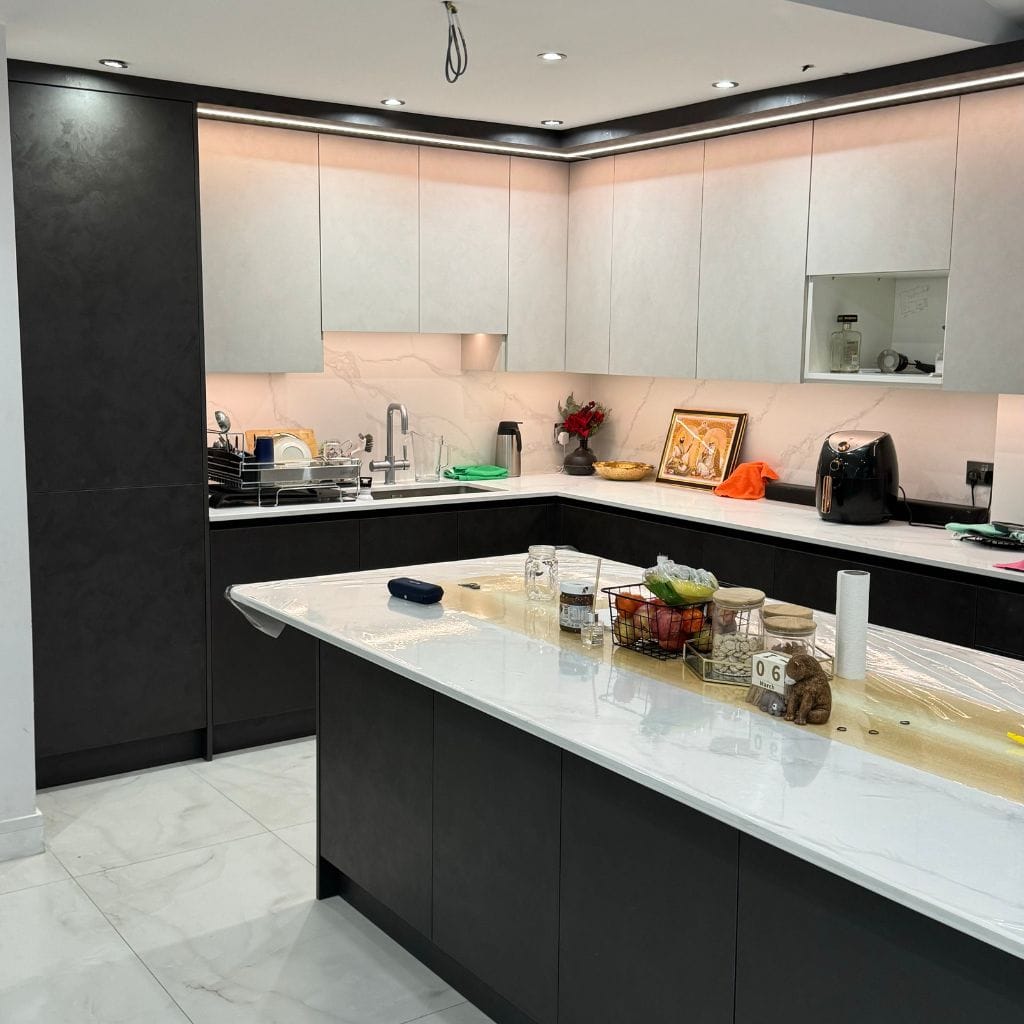 Handleless kitchen in dark graphite stone-effect finish with white quartz island, Calacatta splashback and LED cornice lighting
