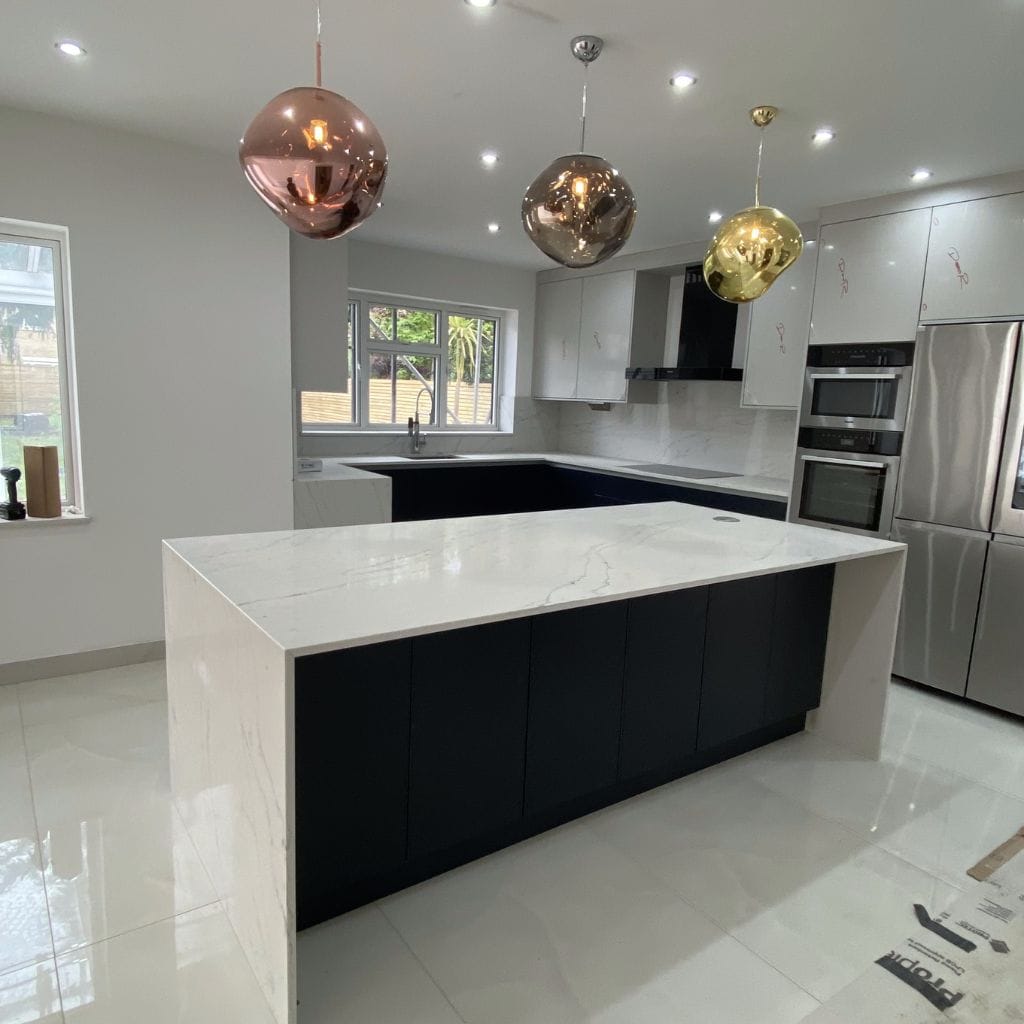 Handleless navy kitchen with Calacatta quartz waterfall island and mixed metallic globe pendant lights