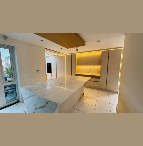 Handleless cream kitchen with large Calacatta quartz waterfall island, amber LED ceiling recess lighting and integrated appliances